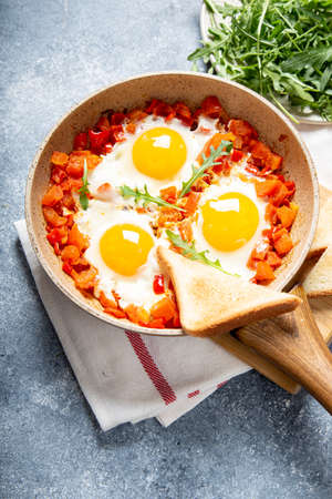 Tasty and Healthy Shakshuka in a Frying Pan. Eggs Poached in Spicy Tomato Pepper Sauce. fried eggs with toast, arugulaの写真素材
