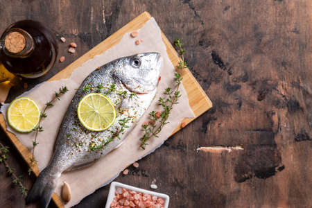 fresh raw dorado fish. dorado fish and cooking ingredients - lime, salt, oil, garlic, thyme and herbsの写真素材