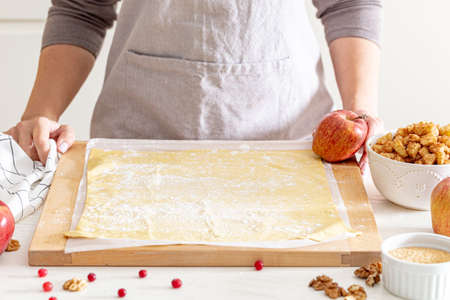 making strudel - dough, apples, cinnamon, nuts, brown sugar. woman preparing apple strudelの写真素材