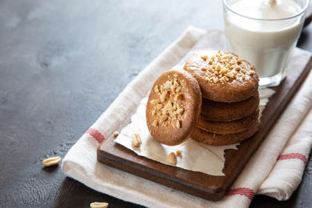 a stack of shortbread homemade cookies with peanuts on a wooden background with milk. peanut cookie.の写真素材
