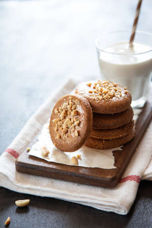 a stack of shortbread homemade cookies with peanuts on a wooden background with milk. peanut cookie.の写真素材