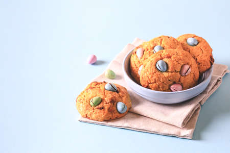homemade cookies chocolate chips with colored candy eggs on a blue background.の写真素材