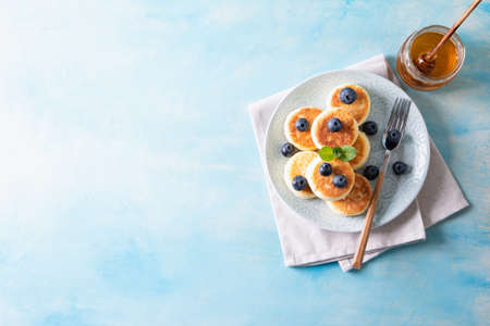 Cottage cheese pancakes. Cheesecakes from cottage cheese, delicious Breakfast, traditional Russian sweet pancakes. With blueberry, mint and honey.の写真素材