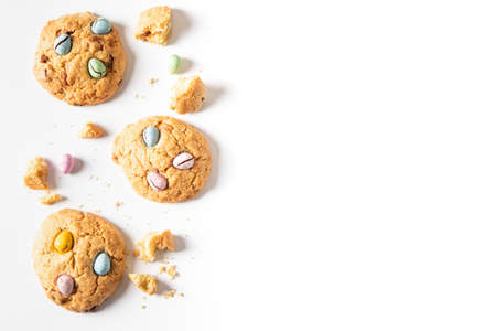 homemade cookies chocolate chips with colored candy eggs on a white background, top view.