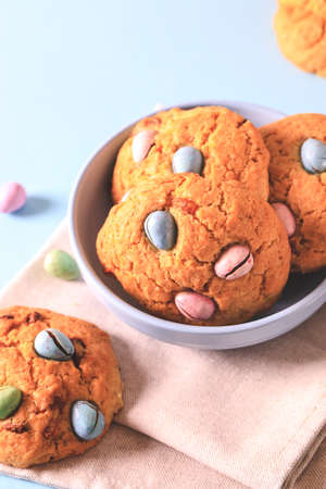 homemade cookies chocolate chips with colored candy eggs on a blue background.