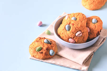 homemade cookies chocolate chips with colored candy eggs on a blue background.の写真素材