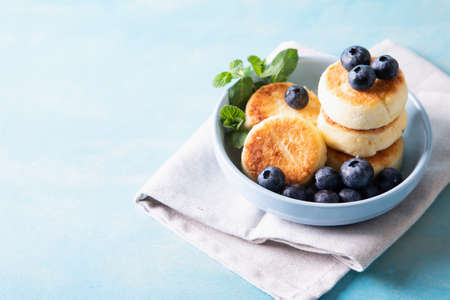 Cottage cheese pancakes. Cheesecakes from cottage cheese, delicious Breakfast, traditional Russian sweet pancakes. With blueberry, mint and honey.の写真素材