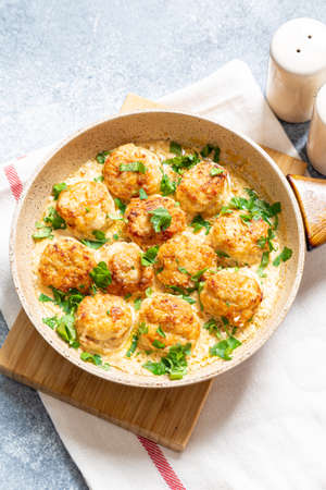 meatballs in white sauce in a frying pan on a gray background, comfortable homemade healthy foodの写真素材