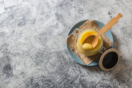 Ghee or clarified butter in jar and wooden spoon on gray table. Top view. Copyspace. Ghee butter have healthy fat and is a common cooking ingredient in many of the Indian foodの写真素材