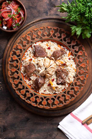 The concept of oriental cuisine. Traditional asian dish - pilaf from rice, vegetables and meat in a plate on a wooden table. background image. top view, copy space, flat layの写真素材
