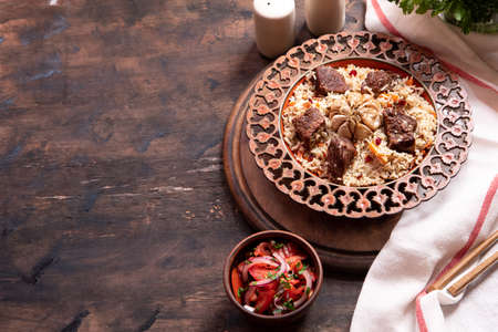 The concept of oriental cuisine. Traditional asian dish - pilaf from rice, vegetables and meat in a plate on a wooden table. background image. top view, copy space, flat layの写真素材