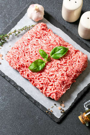 fresh raw minced meat on paper and black slate cutting board, on gray backgroundの写真素材