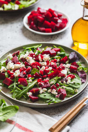 Arugula, Beet and cheese salad with pomegranate and dressing on plate on gray stone kitchen table background, place for text, top viewの写真素材