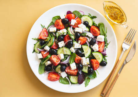 Greek salad of fresh cucumber, tomato, red onion, feta cheese and olives with olive oil. Salad with vegetables and greens. Healthy food, top viewの写真素材