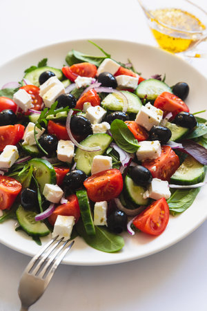 Greek salad of fresh cucumber, tomato, red onion, feta cheese and olives with olive oil. Salad with vegetables and greens. Healthy food, top viewの写真素材