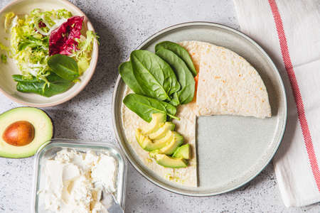 Cooking process for sandwich and ingredients. Process of prepare quesadilla with avocado, salmon, curd cheese and spinach. Trendy wrap hack. step by step. Step 2の写真素材