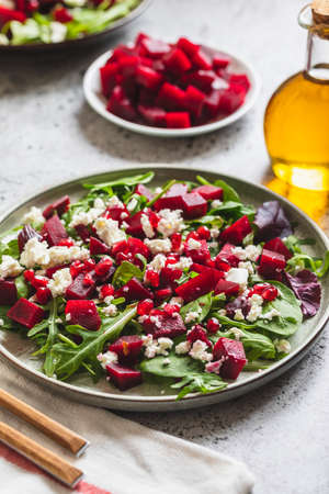 Arugula, Beet and cheese salad with pomegranate and dressing on plate on gray stone kitchen table background, place for text, top viewの写真素材
