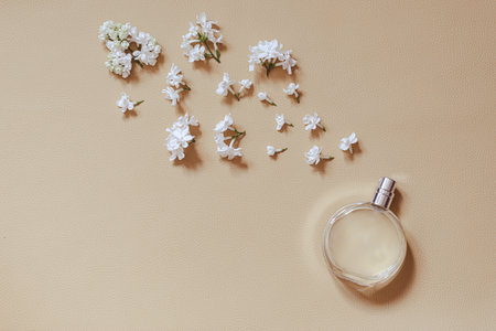 perfumery and floral scent concept. stylish bottle of perfume with spray of lilac flowers on beige background. creative trendy flat lay with space for textの写真素材