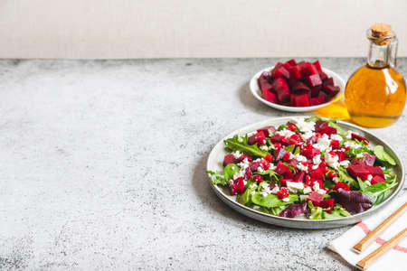 Arugula, Beet and cheese salad with pomegranate and dressing on plate on gray stone kitchen table background, place for text, top viewの写真素材