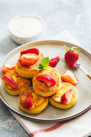 Cottage cheese pancakes, ricotta fritters or syrniki with mint and strawberries. Healthy and delicious morning breakfastの写真素材