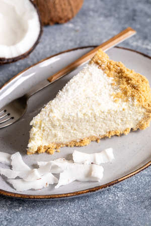 piece of coconut cheesecake on a plate with fresh coconut.の写真素材