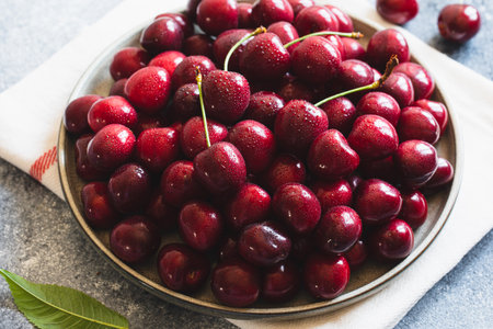 Composition of sweet cherries on a plate with water drops. Summer and harvest concept. Cherry macro. Vegan, vegetarian, raw foodの写真素材