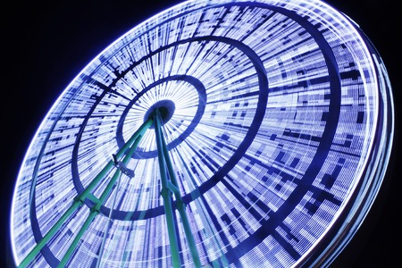 Amusement park at night - ferris wheel and rollercoaster in motionの写真素材