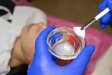 Bowl with face mask. Girl at the beautician beautician applies a mask on the face The mixture is a face maskの写真素材