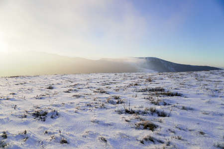 Winter mountains-space for text, frosty blue sky over snowy peaks of rocks and mountains, dry grass growing for wildlife.の写真素材