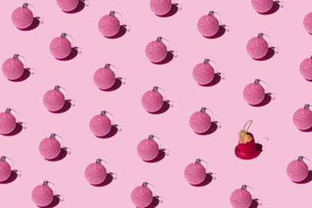 Decorative Christmas pink baubles and a red bell on a pastel background. New year creative pattern.の写真素材