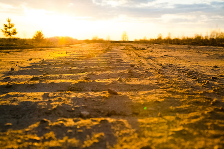 road to sunset, the sun is near the horizon, silhouettes of houses in the setting sunの写真素材