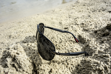 Background for projects related to tourism, travel and recreation, with sun-protective black glasses, sand and water.の写真素材