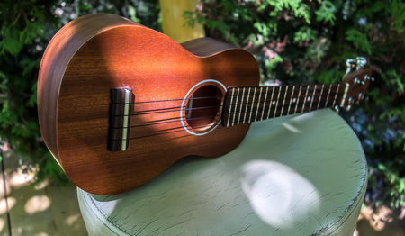 Hawaiian guitar close-up on a nature background in the garden. Music concept. Ukulele on white table in the gardenの写真素材