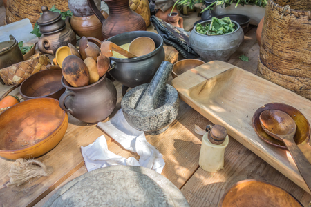 Wooden, clay and wicker-woven rustic crockery on the table. Rural environment, country life. Evening light, the rays of the setting sun, sunset.の写真素材