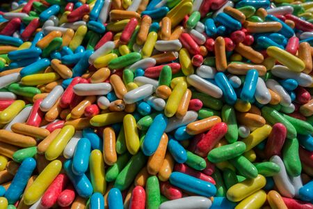 Bright pink, blue, green,white and yellow dragee liquorice close-up, sweet candy backgroundの写真素材