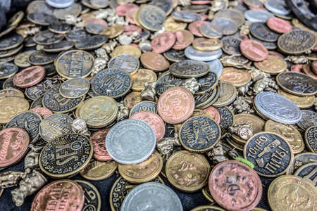 A bunch of comic, funny coins background. Mixed coins are piled in a heap on the blue cloth of the...