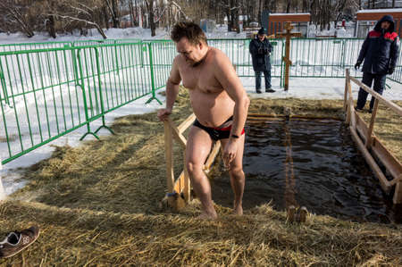 Moscow, Russia, 01/19/2022: Russian people are dipped into an ice hole on the day of the Epiphany. Epiphany bathing in the ice hole in winter. Undressed people in ice water.Traditional ice swimming in Orthodox church Holy Epiphany Day.のeditorial素材