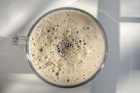 Top view on a beautiful foam beer mug on a white background with shadows from the sun.の写真素材