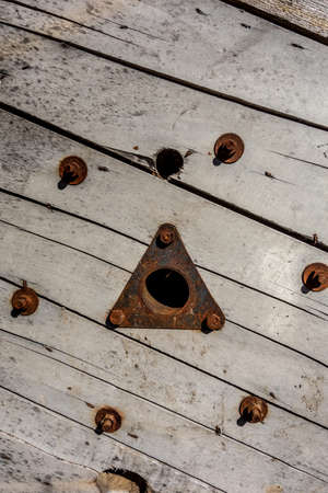 Industrial background made of wooden boards with a rusty triangular hole drilled into them and rusty bolts. Technological background in grunge technique.の写真素材