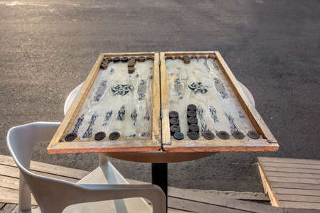 Very old vintage backgammon is lying on the table of a street cafe, ready to play. Spending time with friends playing outdoors.の写真素材