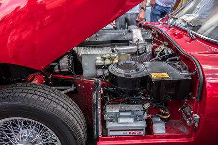 Red classic muscle car 1967 Jaguar E Type Series 4.2 Roadster open hood close up. Big chrome round...