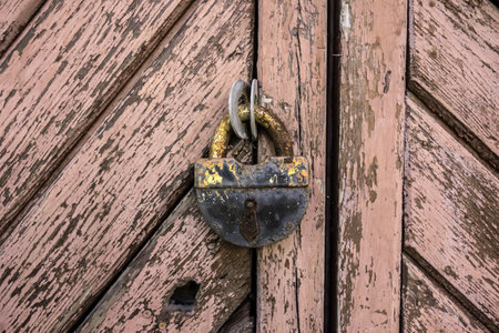 Old rusty vintage lock on a wooden door closeup. Rusty exterior lock on an old wooden door with peeling paint.の写真素材