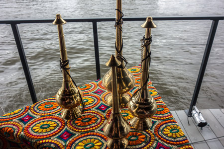 Hand-knitted tablecloth under copper hookahs against the background of water. Vintage floral pattern of Arabic carpet close-up. Boating on a Qatari yacht.の写真素材