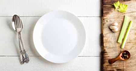 Cooking background concept. Empty white plate, spice and cutlery over wooden background.の写真素材