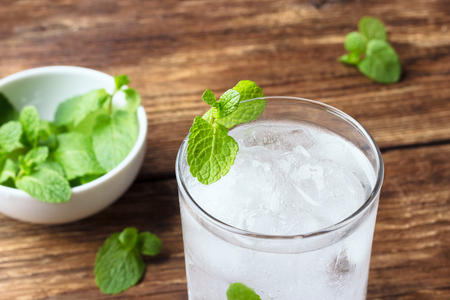 Glass of water with ice and mint on wooden background.の写真素材
