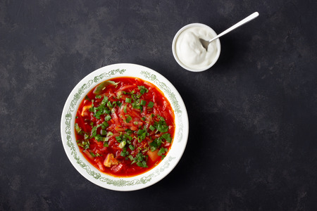 Traditional  ukrainian russian traditional beet red soup - borscht with sour cream on black stone...
