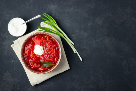 Vegetarian beet red soup - borscht with sour cream on black stone background. Top view.の写真素材
