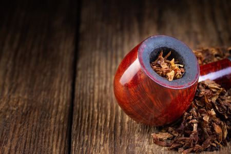 Lacquered smoking pipe and tobacco pile on vintage wooden table. Copy space.の写真素材