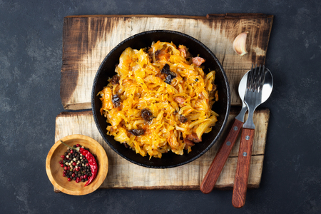 Traditional dish of polish cuisine - Bigos from fresh cabbage, meat and prunes. Top view. Dark background.の写真素材