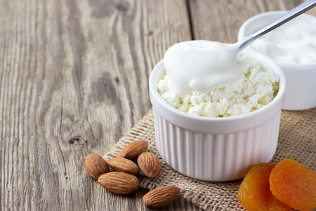 Healthy breakfast. ?ottage cheese, cream sour, nuts and dried apricots on wooden rustic table.の写真素材